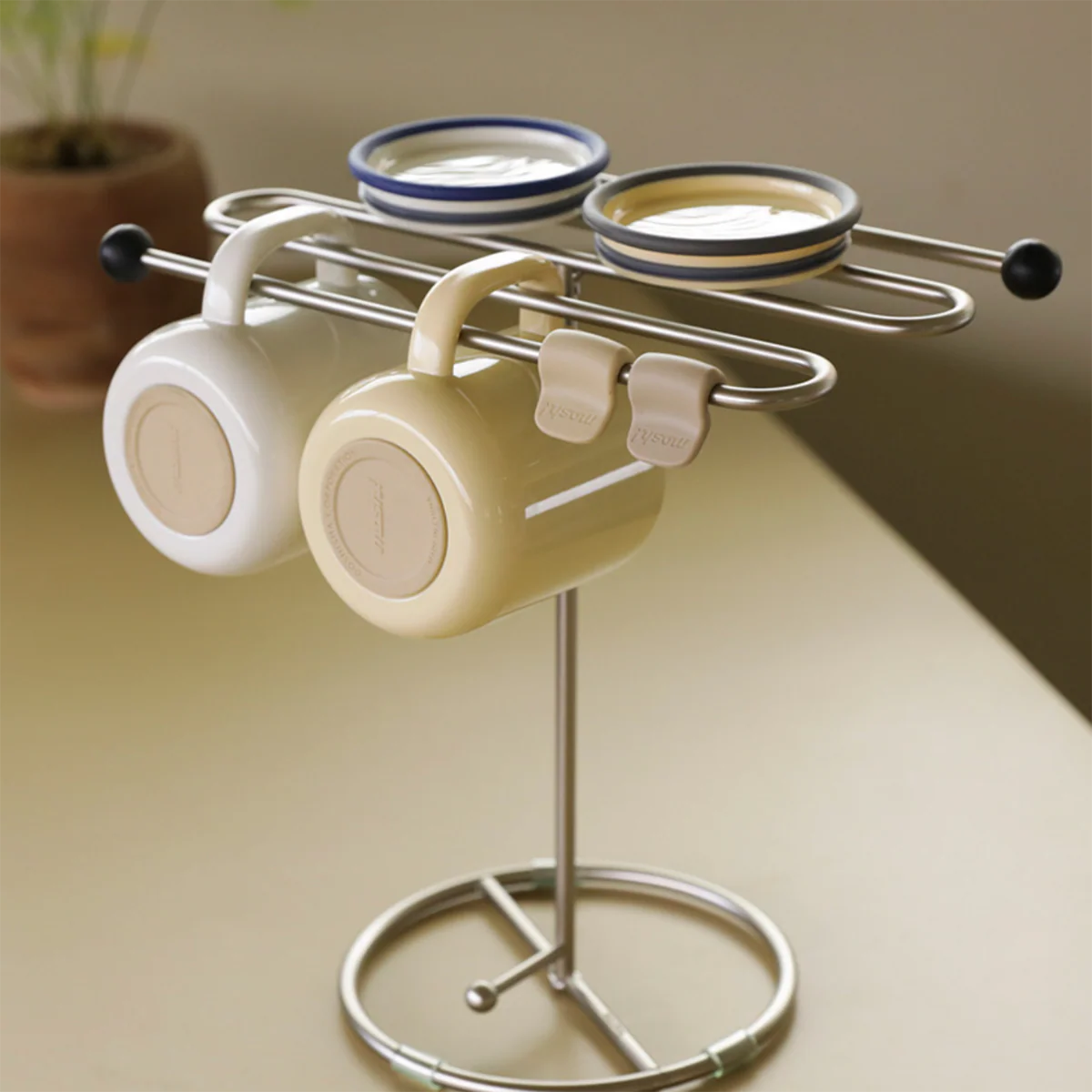 Metal mug rack holding three mugs on a countertop.